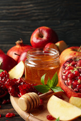 Apples, pomegranate and honey on wooden background, close up