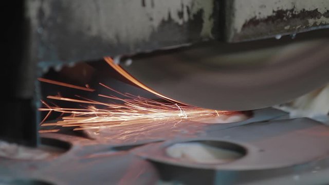 Metal grinding machine during grinding out the metal detail in factory. Grinding smooths steel and iron using modern equipment. Machinery and professional equipment concept
