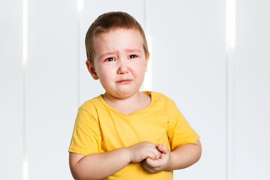 Crying Baby Boy In A Yellow Shirt Covers His Face With Hands And Shouts, Tears