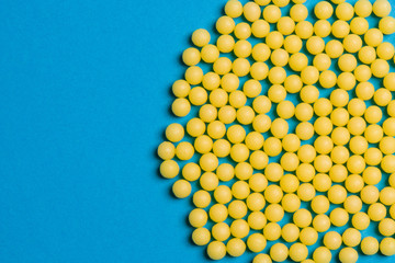 Yellow medical pills on blue background with copy space for text. Alternative homeopathy medicine, healthcare and wellness concept.