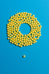 Obraz premium Yellow medical pills on blue background with copy space for text. Alternative homeopathy medicine, healthcare and wellness concept.