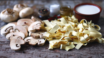 Raw pasta, mushrooms, cream and spices. Products for the preparation of mushroom pasta with cream. Mushrooms pasta recipe.