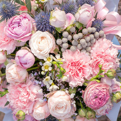 Woman florist making a lovely Flower composition in round blue hat box of Brunia, pink roses, blue Eryngium, white Chamelaucium, Dianthus Flowers bouquet. Copy spase