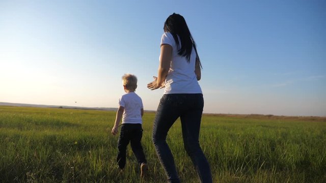 A young mother plays with a child on the street. A woman runs after a small cheerful son. Happy family having fun outdoors.