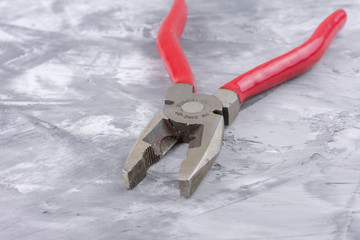 Pliers with red handles on a grey background