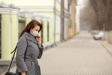 Fototapeta premium Woman wearing protective medical mask an empty European street, outdoors. Concept self-care