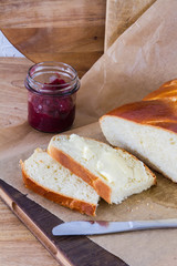Sweet roll called challah with butter. On woodden board.