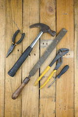 Assortment of hand tools spread out on rough wooden background. 