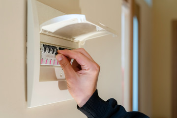 Hand switching power switch on a fusebox. Close up of electrician checking fuse box knob