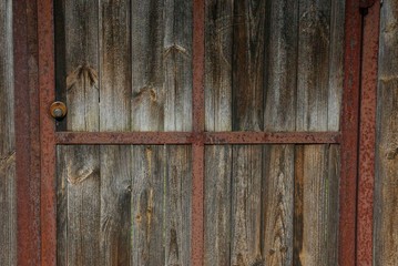 wooden texture of gray boards on an old door with rusty iron brown plates