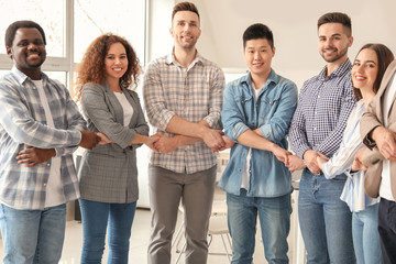 Group of people holding hands together indoors. Unity concept