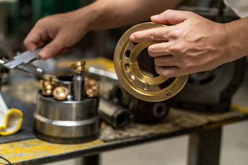 Professional mechanic man holding Valve plate of the hydraulic piston pump to inspection and repair maintenance heavy machinery