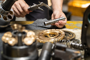 Professional mechanic man holding Valve rod of the hydraulic piston pump to inspection and repair...