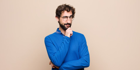 young handsome man looking serious, confused, uncertain and thoughtful, doubting among options or...