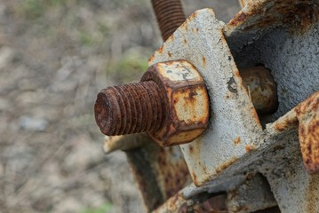 one brown rusty bolt with nut on a gray iron plate in the street