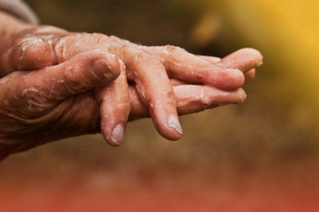 Fototapeta premium Old wrinkled hands of a grandmother close-up. An elderly woman disinfects her hands in connection with the spread of coronavirus infection. Grandma of my hand close-up.
