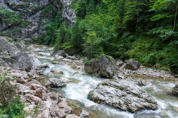 Mountain forest stream with fast flowing water and rocks, long exposure.
