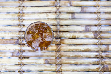 Top view of iced tea on bamboo wooden background with shadow and sunshine.