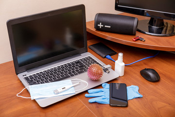 Hygiene in the home office. View of desk, desktop with laptop, phone and medical face mask. Global pandemic Coronavirus ncov COVID-19. Remote work or distance learning. Stay at home. Copy space.