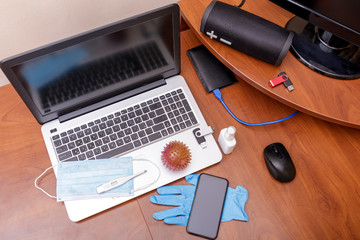 Hygiene in the home office. View of desk, desktop with laptop, phone and medical face mask. Global pandemic Coronavirus ncov COVID-19. Remote work or distance learning. Stay at home. Copy space.