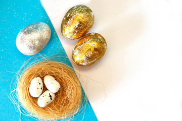 Gold and silver Easter eggs with nest on a blue background. Easter concept. Happy Easter. Copy space