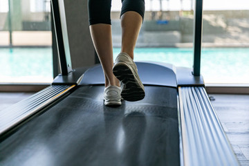 Fototapeta na wymiar Legs of woman running on a treadmill in gym