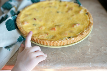 Children's hand reaches for breaking a piece of cake