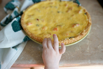 Children's hand reaches for breaking a piece of cake