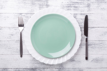 Empty green mint plate and cutlery on wooden background. Stylish table setting. Copy space. Top view