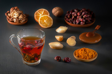 Medicinal herbal tea in a glass cup, ginger, walnut, turmeric, honey, lemon and dry rosehip berries - a means to increase immunity from the virus