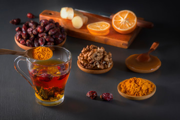 Medicinal herbal tea in a glass cup, ginger, walnut, turmeric, honey, lemon and dry rosehip berries - a means to increase immunity from the virus