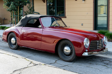 Classic 1951 Simca 8 Sport convertible car looks pretty from 3/4 front view with roof top up.