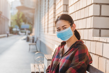 Asian woman sitting on a  bench wearing face mask  to protect virus and dust