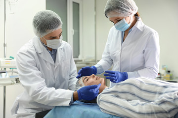 Doctor and nurse preparing female patient for cosmetic surgery in clinic