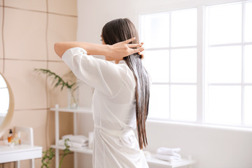 Beautiful young woman applying coconut oil on her hair at home - obrazy, fototapety, plakaty