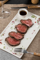 slices of roast beef appetizer with balsamic sauce on white plate on the table at restaurant