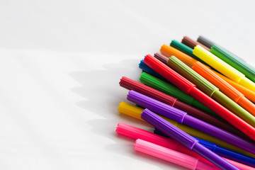 Multi-colored markers in large numbers on the white table