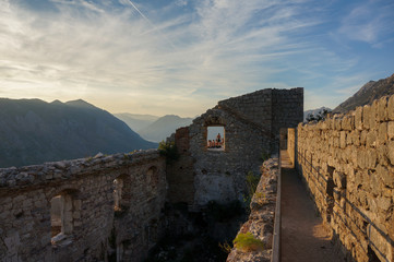 Ruined fortress of St. Ivan on top of the mountain in the last rays of the setting sun. Landscape scene. Kotor, Montenegro.