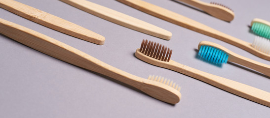 Set of bamboo toothbrushes. Different color. Ecology wood tooth brush group. Grey background. Natural oral hygiene. Dental zero waste protection