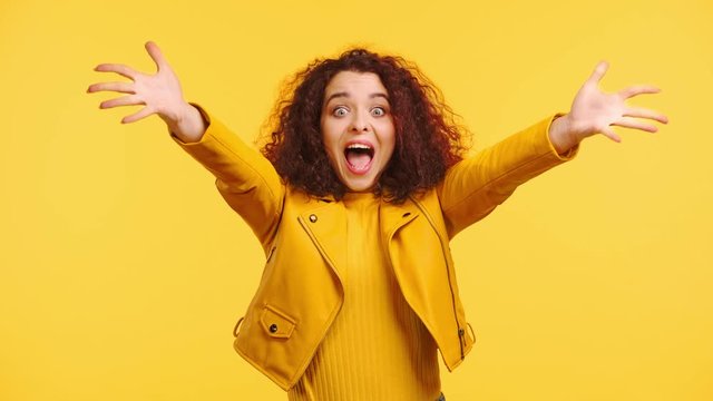 excited, happy girl holding crossed fingers and gesturing isolated on yellow