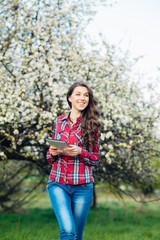 Attractive woman with tablet in blooming garden