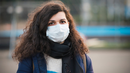 Close-up portrait young europeans woman in protective disposable medical face mask walking outdoors. Concept of health care