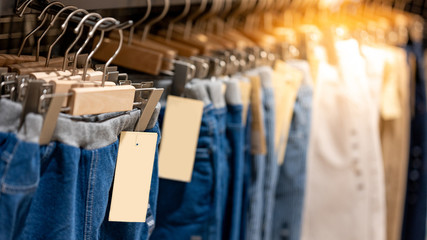 Jeans or Denim pants (trousers) hanging on rack in clothes shop. Fashion product collection in clothing store for selling. Textile industry and business concept