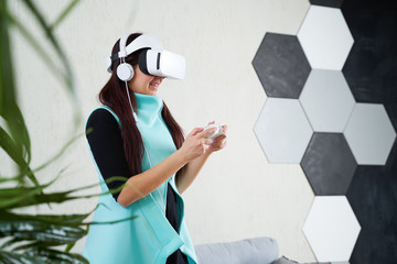 Woman with virtual reality headset and gamepad is playing game.