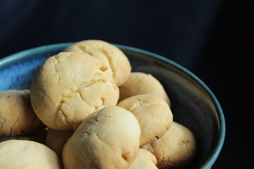 Artisan biscuits: homemade sugar dessert with fragrant lemon zest and citrus juice, delicious cookies for tea time at home, stored in beautiful handmade blue pottery bowl on the kitchen table.