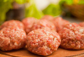 Raw meat balls on the wooden cutboard.
