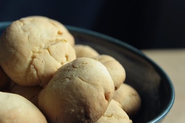 Artisan biscuits: homemade sugar dessert with fragrant lemon zest and citrus juice, delicious cookies for tea time at home, stored in beautiful handmade blue pottery bowl on the kitchen table.