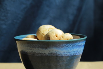 Artisan biscuits: homemade sugar dessert with fragrant lemon zest and citrus juice, delicious cookies for tea time at home, stored in beautiful handmade blue pottery bowl on the kitchen table.