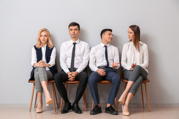 Obraz premium Young business people waiting in line near light wall