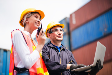 Young Caucasian man and woman worker Check and control loading freight Containers by use computer laptop and radio at commercial shipping dock felling happy. Cargo freight ship import export concept